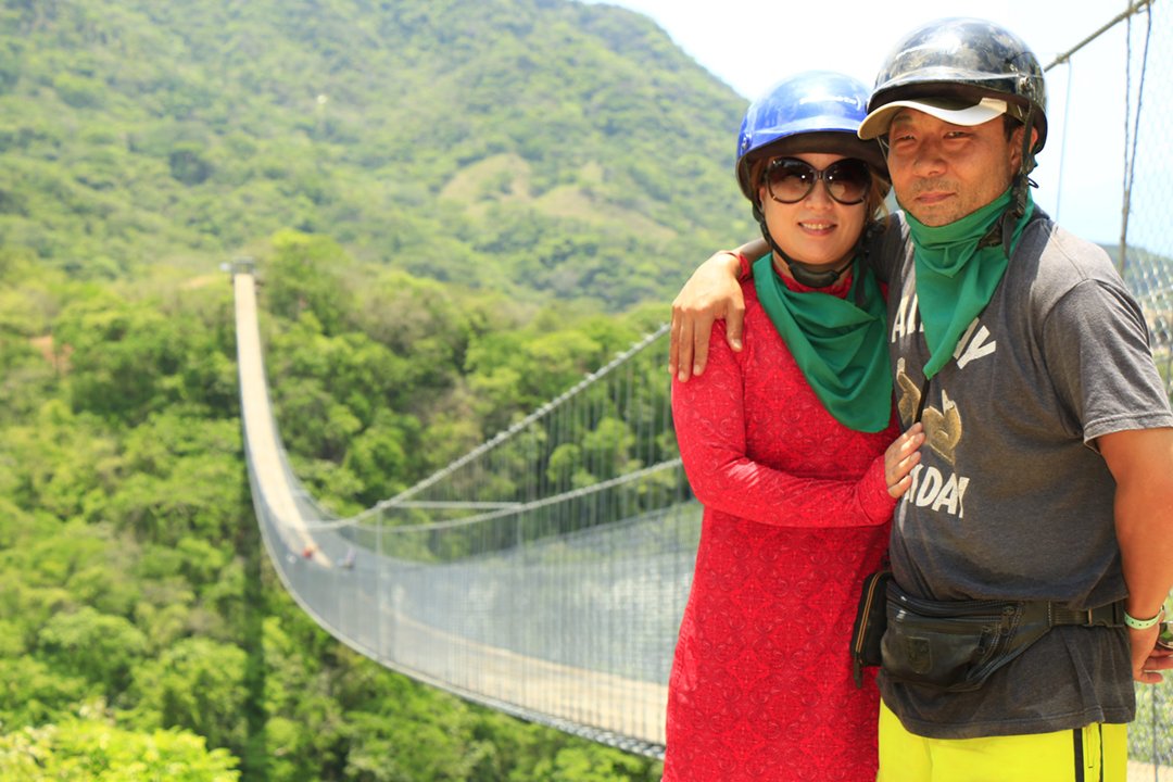 Couple wearing helmets and bandanas on an RZR tour at the Jorullo Bridge, Puerto Vallarta